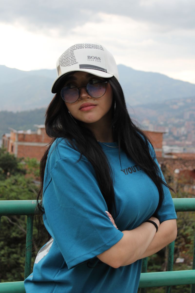 Modelo con gorra blanca del catálogo, con Medellín de fondo