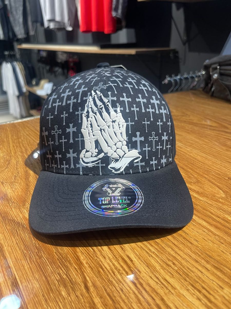 Gorra negra manos en oración estampado de cruces